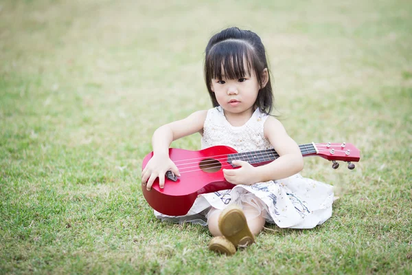 Aziatische meisje spelen gitaar in de tuin Rechtenvrije Stockfoto's