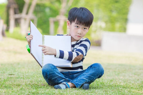 Petit garçon asiatique lire le livre dans le jardin — Photo