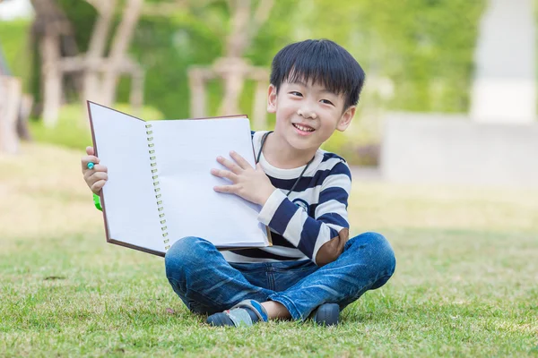 Pouco ásia menino ler o livro no o jardim — Fotografia de Stock