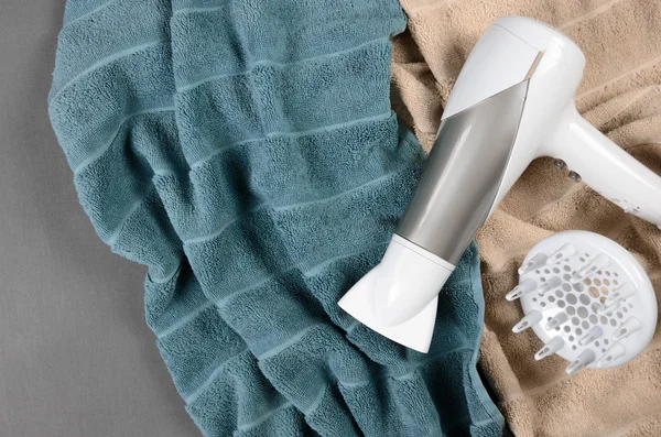 Secador de cabelo branco em toalhas bege e azul esverdeado. Vista superior — Fotografia de Stock