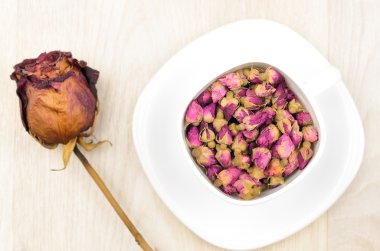 Güller beyaz Kupası ve ahşap masa üzerinde kuru gül çiçek