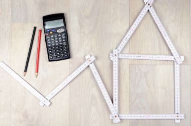 bir ev, iki kalem ve hesap makinesi w üzerinde şekillendirme beyaz metre aracı