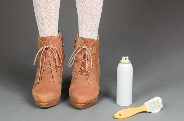 Vrouwelijke benen in bruin suède laarzen op een grijze achtergrond. Reiniging — Stockfoto