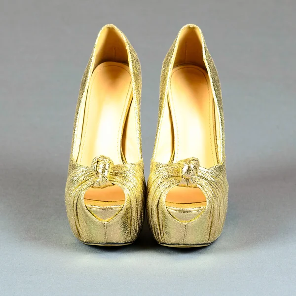 Zapatos de tacón alto dorados sobre fondo gris —  Fotos de Stock