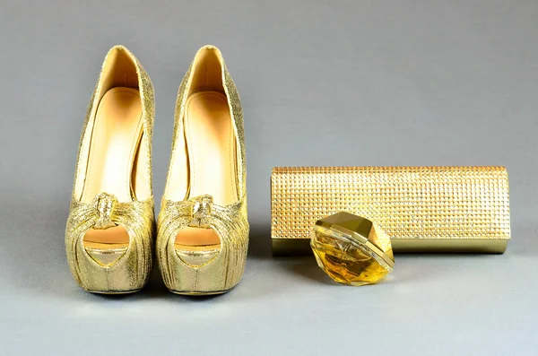 Zapatos de tacón alto de oro, bolso de embrague y perfume en un fondo gris —  Fotos de Stock