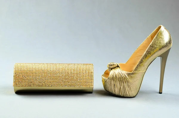 Zapato de tacón alto dorado y bolso de embrague sobre fondo gris —  Fotos de Stock
