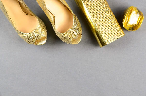 Scarpe con tacco alto oro, pochette e profumo su sfondo grigio — Foto Stock