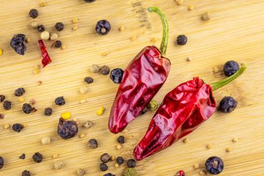 Bir doğrama tahtasının üzerinde iki kırmızı biber ve biraz baharat (hardal, ardıç).
