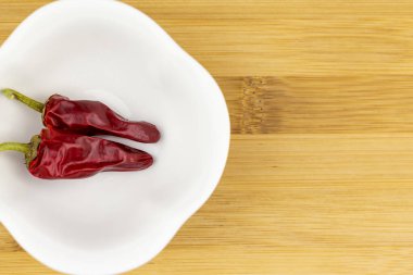 Kırmızı biberler doğrama tahtasındaki beyaz kasede.