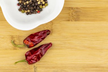 İki kırmızı biber ve doğrama tahtasındaki beyaz kasede biber çekirdeği seçimi.