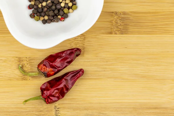 İki kırmızı biber ve doğrama tahtasındaki beyaz kasede biber çekirdeği seçimi.