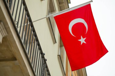 Türk bayrağı bulutlu gökyüzüne karşı binanın duvarında dalgalanıyor