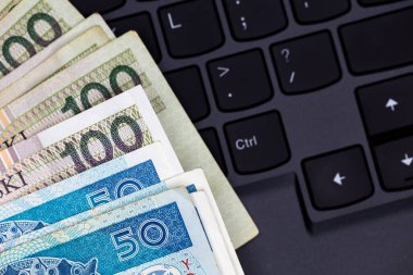 Siyah dizüstü bilgisayar klavyesine yerleştirilmiş Polonya 50 ve 100 PLN banknot seti. Fotoğraf yapay, yumuşak ışık altında çekildi