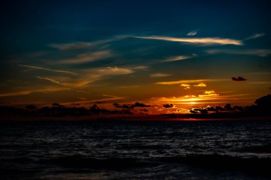  Deniz kenarında gün batımı. Yumuşak dalgalar, sakin deniz manzarası. İklimsel aydınlatma koşullarında yapıldı.