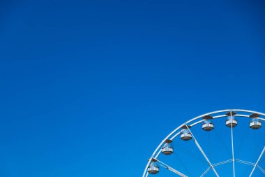 Mavi bir arka planda beyaz bir dönme dolap. Fotoğraf iyi ışıklandırma koşullarında çekildi