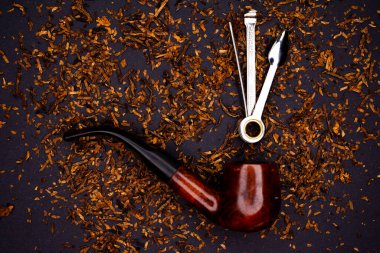 Sigara piposu ve aksesuarları dağınık tütünün arka planına karşı temizlemek için..