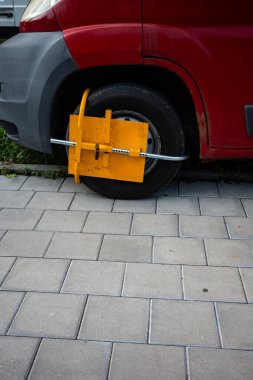 Yasak yere park edilmiş arabanın sarı tekerlek kıskacı. Şehir park kurallarını çiğnemenin cezası. Gündüz çekilmiş.. 