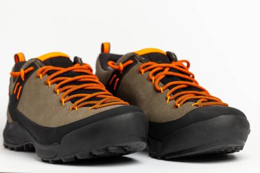 Beyaz arka planda renkli turuncu bağcıklı bej yürüyüş botları. Fotoğraf yapay ışıklandırma altında çekildi.