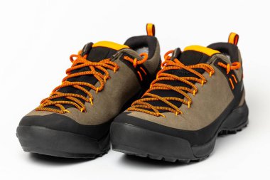 Beyaz arka planda renkli turuncu bağcıklı bej yürüyüş botları. Fotoğraf yapay ışıklandırma altında çekildi.