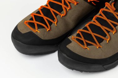 Beyaz arka planda renkli turuncu bağcıklı bej yürüyüş botları. Fotoğraf yapay ışıklandırma altında çekildi.