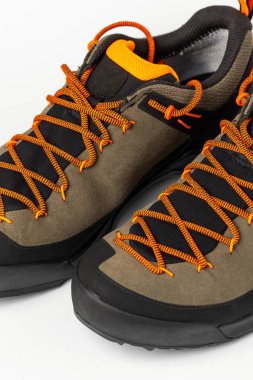 Beyaz arka planda renkli turuncu bağcıklı bej yürüyüş botları. Fotoğraf yapay ışıklandırma altında çekildi.