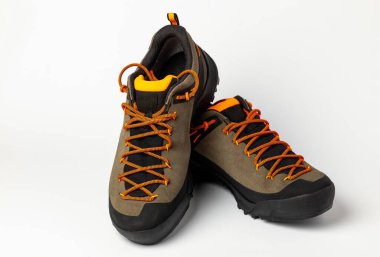 Beyaz arka planda renkli turuncu bağcıklı bej yürüyüş botları. Fotoğraf yapay ışıklandırma altında çekildi.