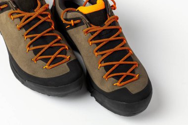 Beyaz arka planda renkli turuncu bağcıklı bej yürüyüş botları. Fotoğraf yapay ışıklandırma altında çekildi.