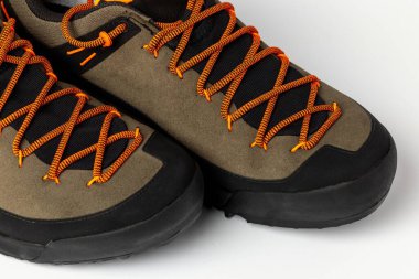 Beyaz arka planda renkli turuncu bağcıklı bej yürüyüş botları. Fotoğraf yapay ışıklandırma altında çekildi.