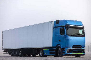 Çakıl bahçesine park etmiş beyaz karavanı olan mavi bir kamyonet. Fotoğraf bir günde çekilmiş..