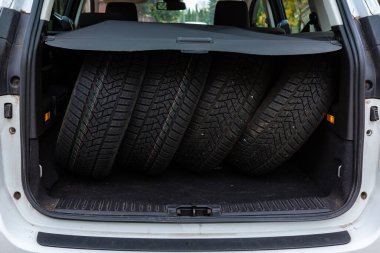 Bir yolcu kamyonunun bagajında dört lastik seti. Lastikler mevsimsel değişikliklere hazır. Fotoğraf gündüz vakti doğal ışık altında çekildi..