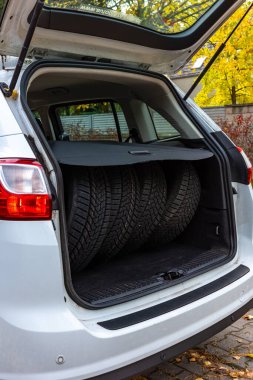 Bir yolcu kamyonunun bagajında dört lastik seti. Lastikler mevsimsel değişikliklere hazır. Fotoğraf gündüz vakti doğal ışık altında çekildi..