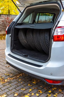 Bir yolcu kamyonunun bagajında dört lastik seti. Lastikler mevsimsel değişikliklere hazır. Fotoğraf gündüz vakti doğal ışık altında çekildi..