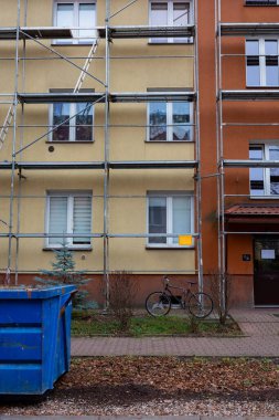 Üç katlı bir apartmanın ön cephesinin yenilenmesi. Binanın duvarına çelik iskeleler kuruldu..