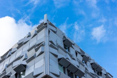 Modern bir konut ve ofis binasının gri cephesi. Bina duvarı açık bulutlu mavi bir gökyüzüne kurulmuş..