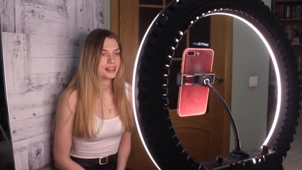 Mulher branca loira vlogging de casa com anel de luz e telefone vermelho — Vídeo de Stock