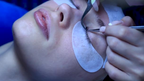 Primer plano cosmetólogo pone las extensiones de pestañas en la mujer blanca, procedimiento de belleza — Vídeos de Stock