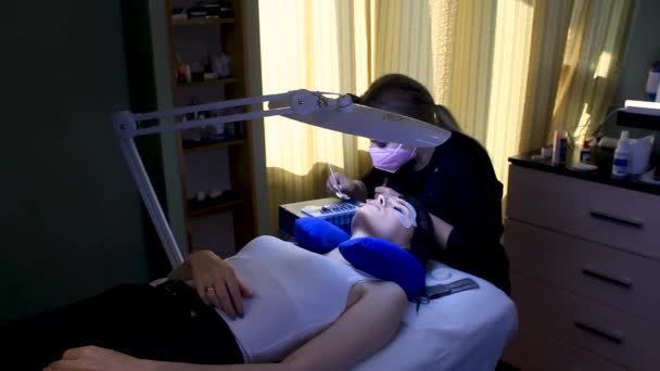 Cosmetoloog zet nep wimpers extenties op vrouw, schoonheid procedure — Stockvideo