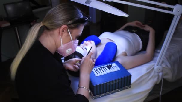 Cosmetologist põe extensões de pestanas falsas na mulher, procedimento de beleza — Vídeo de Stock