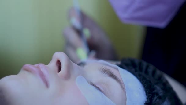 Närbild Kosmetolog sätter falska ögonfransar förlängningar på kvinnan, skönhet förfarande — Stockvideo