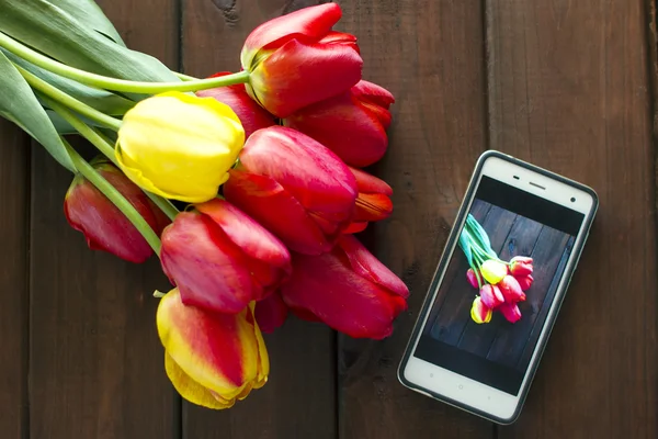 Красивий букет тюльпанів на столі, фотографії, зроблені по телефону — стокове фото