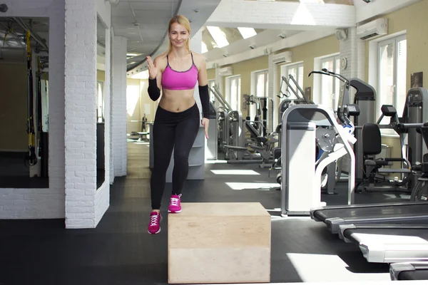 Beautiful athletic girl doing exercises. The blonde in the gym. — Stock Photo, Image