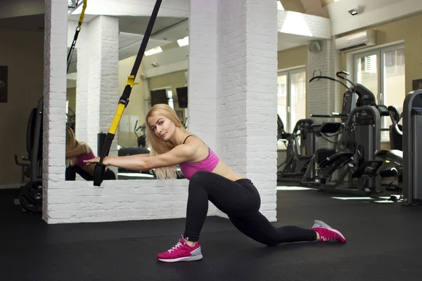 Beautiful athletic girl doing exercises. The blonde in the gym. — Stock Photo, Image