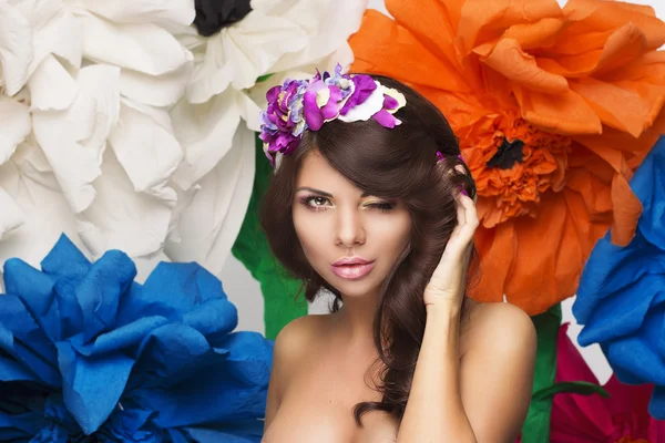 Menina bonita modelo pisca com um aro de flores no cabelo — Fotografia de Stock