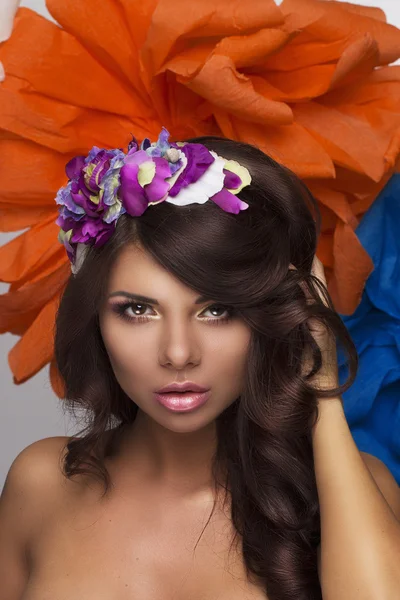 Modelo de menina bonita com um aro de flores no cabelo e grandes flores no fundo — Fotografia de Stock