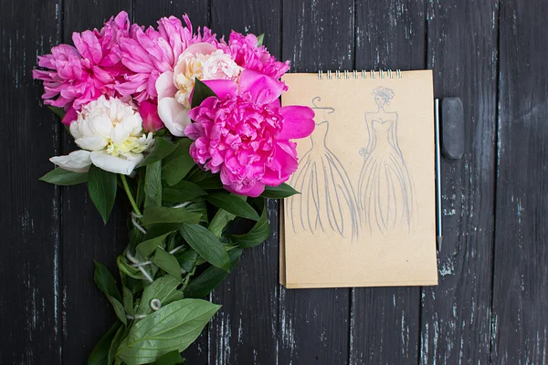 Many beautiful colored peonies on wooden background