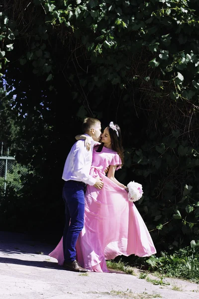 La jeune mariée dans une belle robe embrasse marié à un mariage avec un bouquet de fleurs — Photo