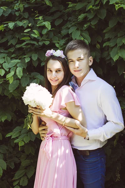 De jonge bruid in een mooie jurk omarmt bruidegom op een bruiloft met een boeket van bloemen — Stockfoto