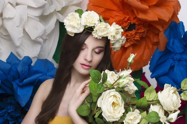 Retrato de beleza de um modelo com uma coroa de flores na cabeça, segurando um buquê de rosas e maquiagem bonita — Fotografia de Stock