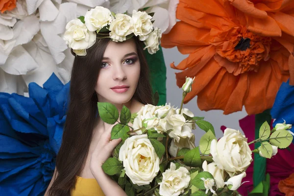 Retrato de beleza de um modelo com uma coroa de flores na cabeça, segurando um buquê de rosas e maquiagem bonita — Fotografia de Stock