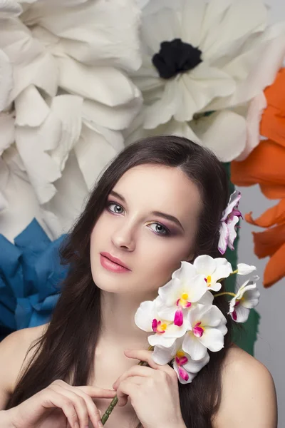 Beauty porträtt av en modell med en krans av blommor på hennes huvud, håller en bukett med rosor och vackra makeup — Stockfoto